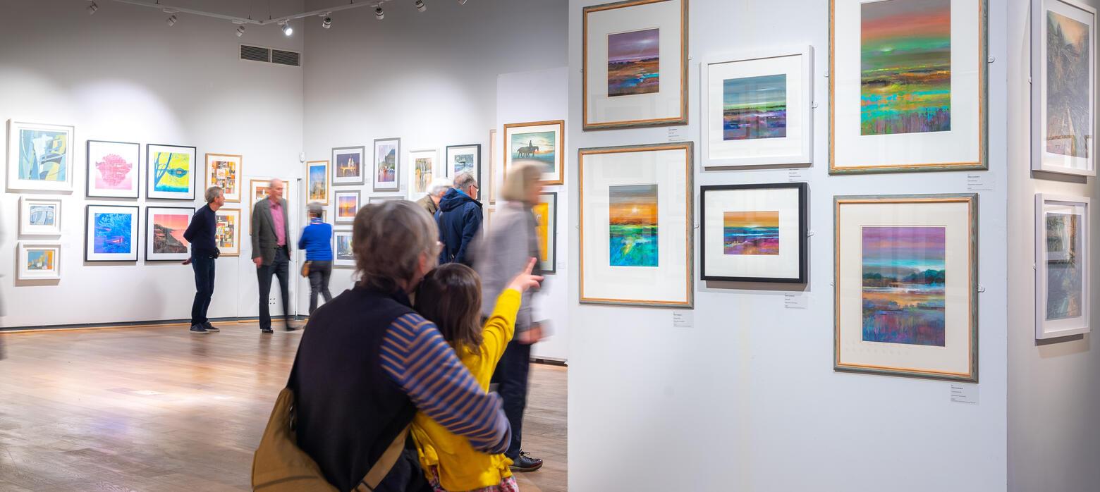 an older woman and a young child sat on a bench in the west gallery looking at a wall of art
