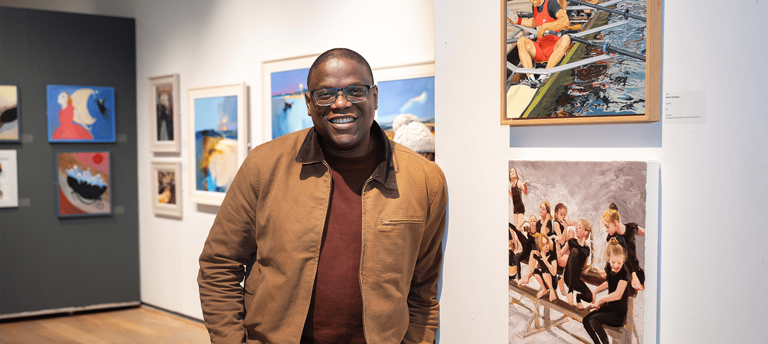Adebanji Alade, first black president of the ROI stands next to his artwork at Mall Galleries