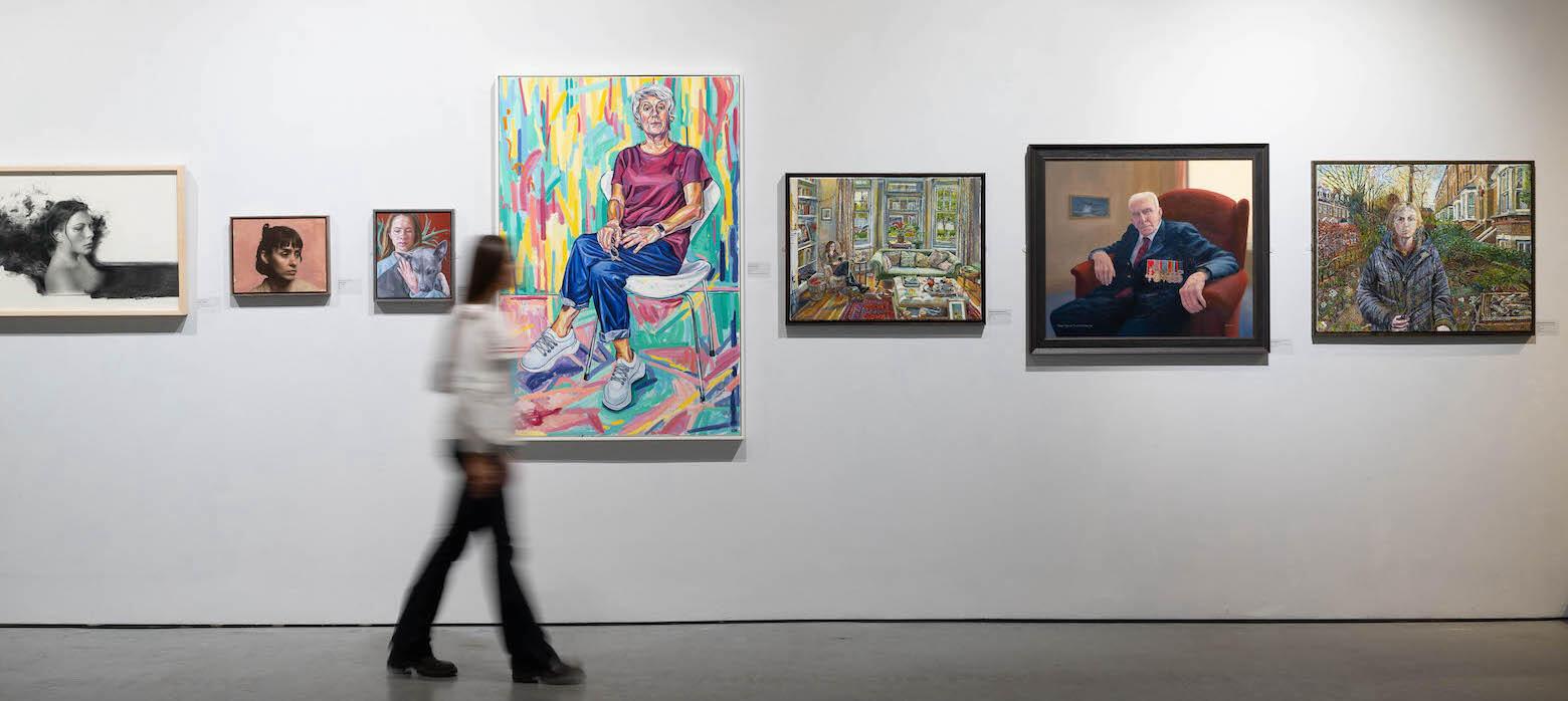 Visitor observing a wall of portrait paintings