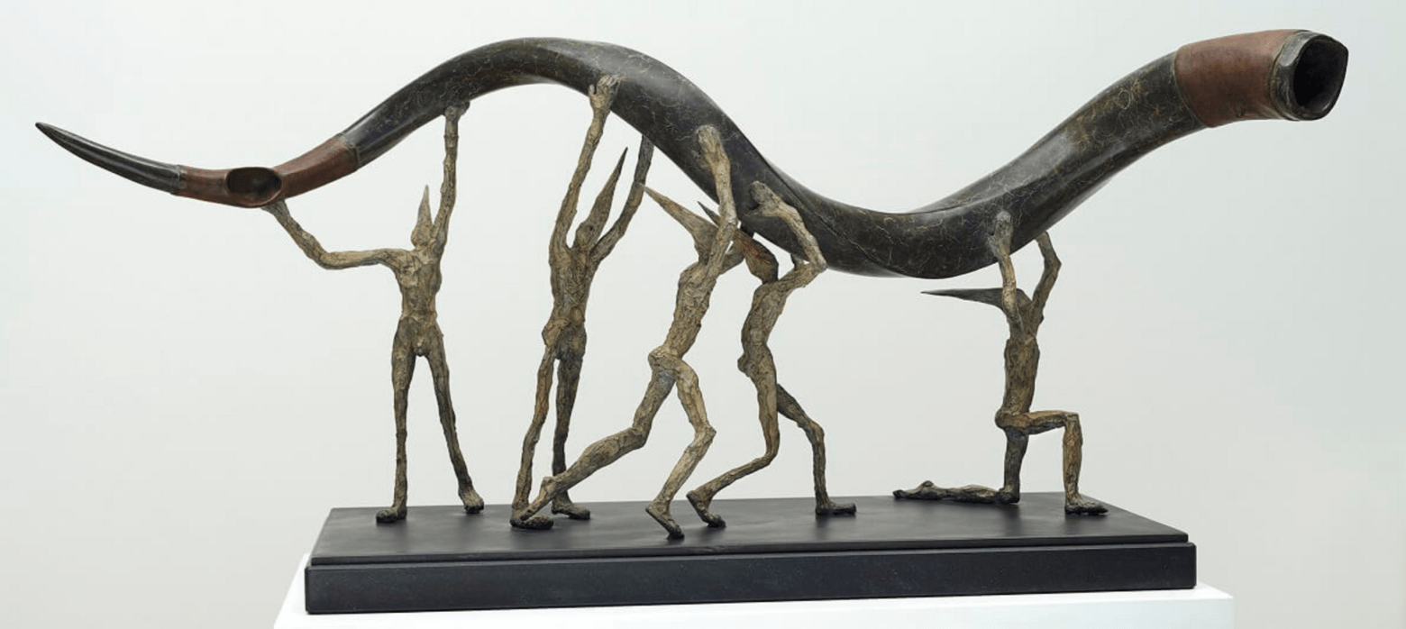 metal sculpture of 5 figures holding a curly horn