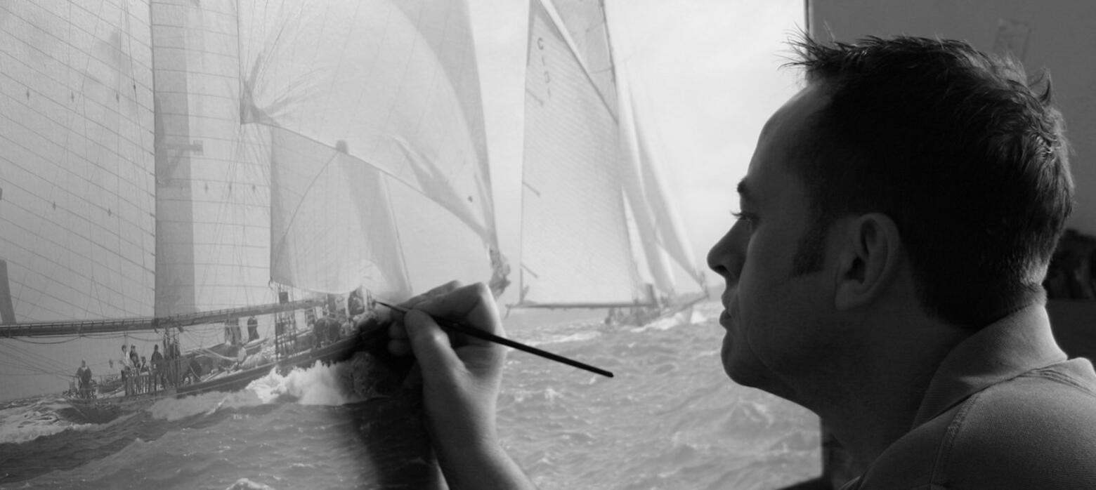 Black and White photograph of Jamie Medlin working on large yacht painting in studio