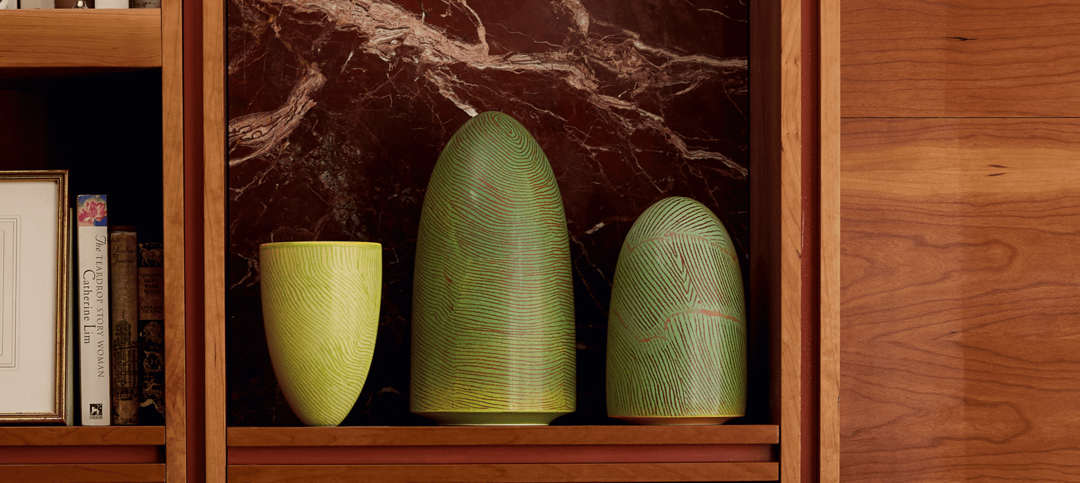 3 green sculptures on a wooden shelf