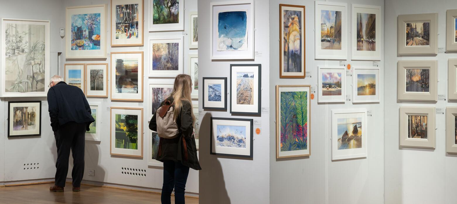 A visitor looking closely at a watercolour painting. 