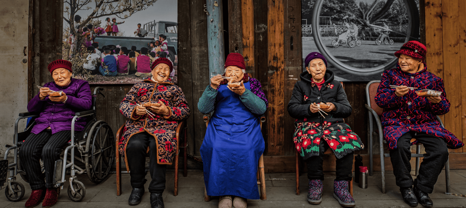 5 elderly women sat on chairs eating food