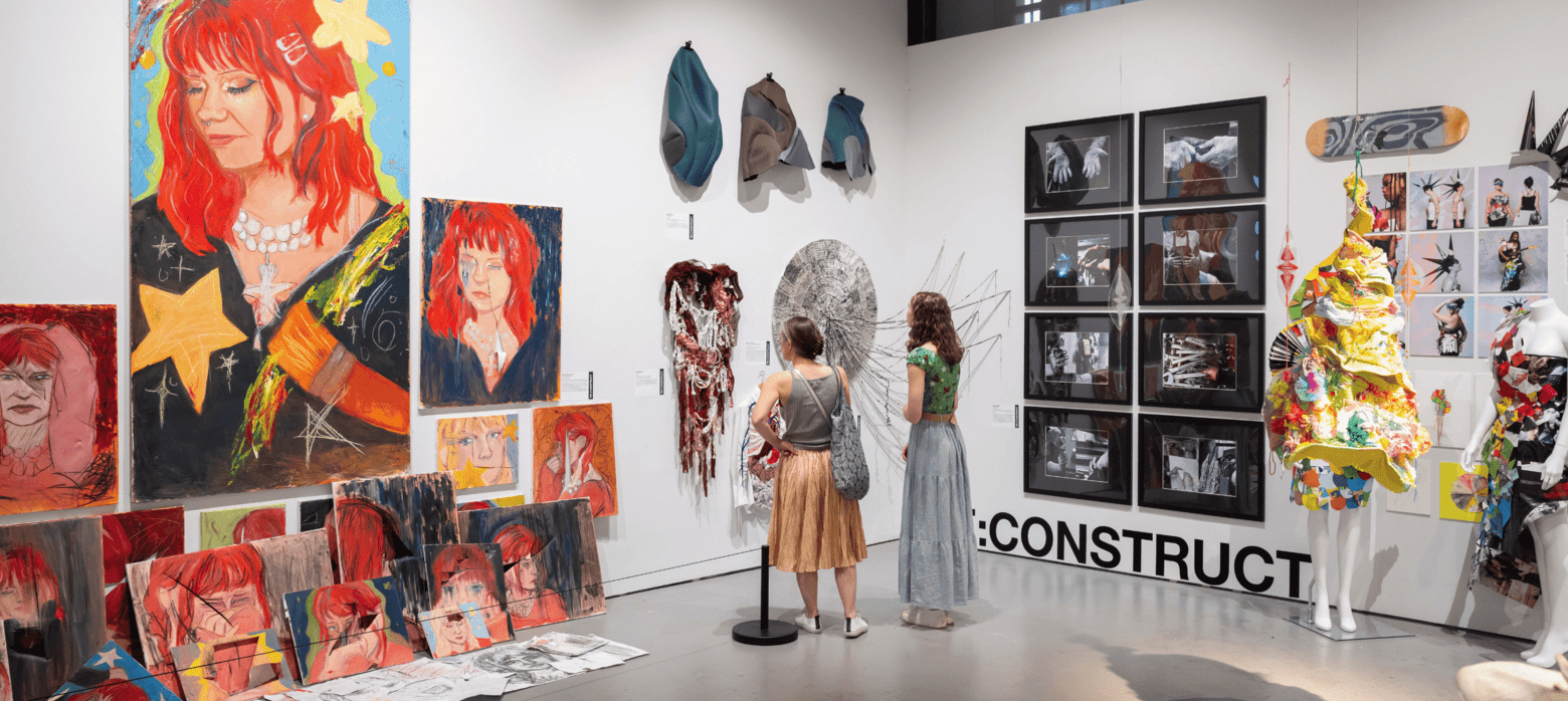 2 visitors looking at a wall of student art