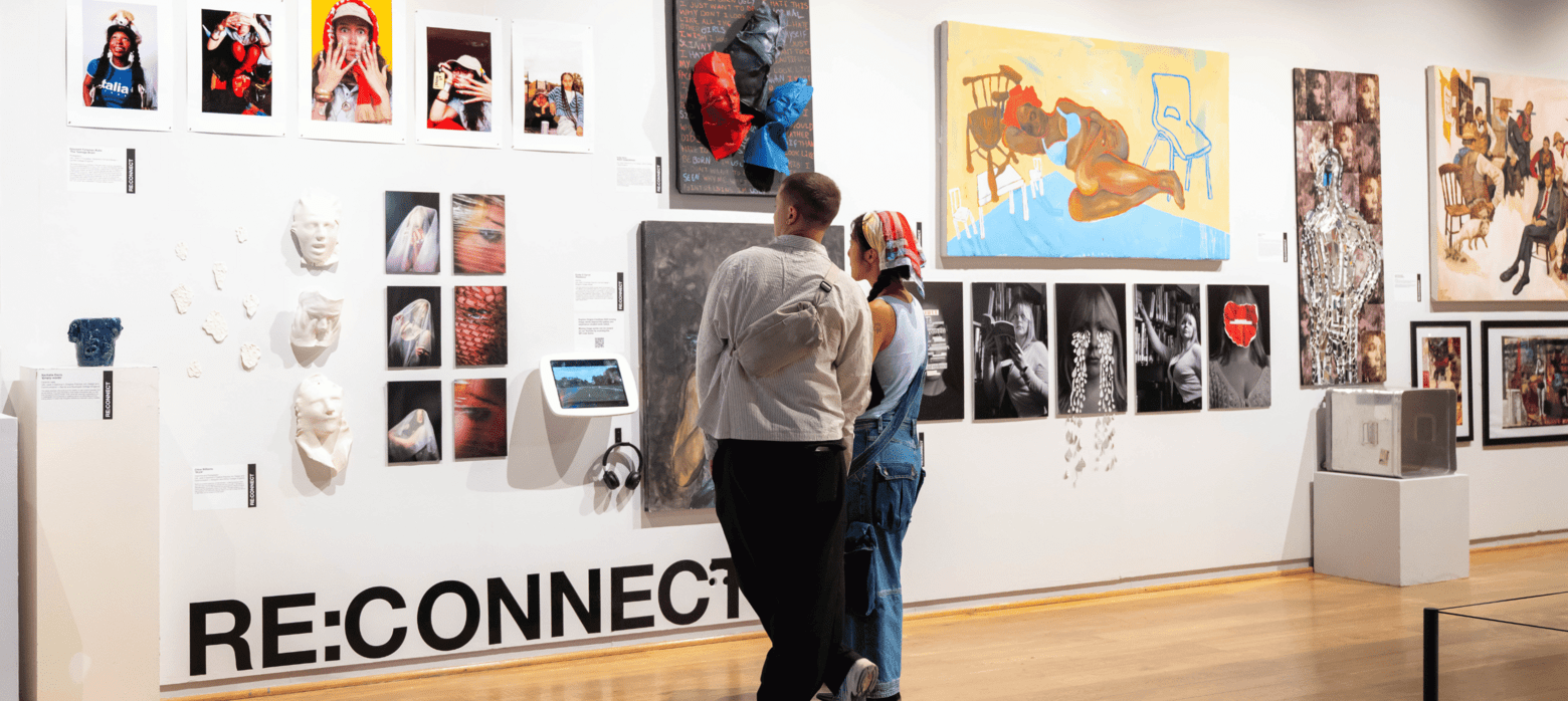 2 visitors looking at a wall of student art