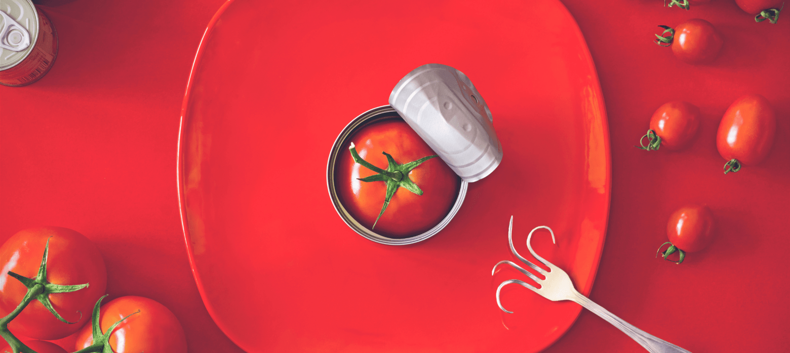 artistic photo og a tomato in a can which is on a red plate