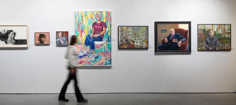 Visitor observing a wall of portrait paintings