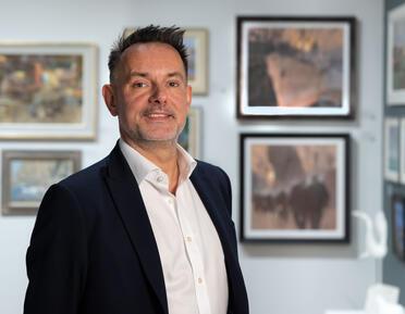 Tom King stands in front of gallery walls