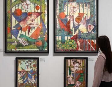 A visitor views four wall-mounted water colour paintings.