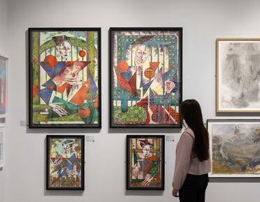 A visitor views a collection of wall-mounted water colour paintings. 