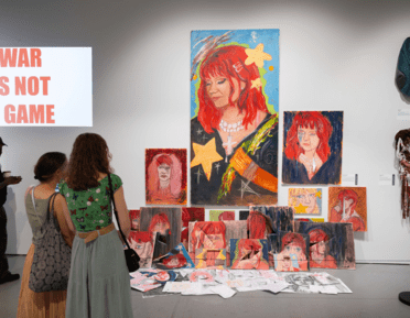 2 people looking at a wall of art in the East Gallery