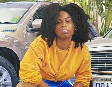 Image of a black woman crouching in front of cars