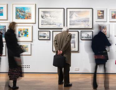 five people looking at paintings in a gallery