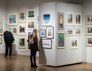 A visitor looking closely at a watercolour painting. 