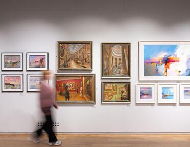 A blurry figure walks past four paintings of an art gallery