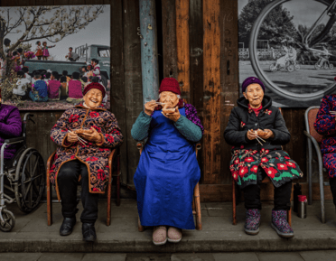5 elderly women sat on chairs eating food