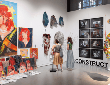 2 visitors looking at a wall of student art