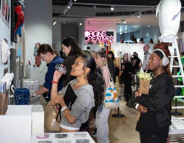 Group of people look at work on wall with bright pink neon sign behind