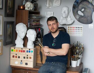 Sam Clayden Artist in workshop holding brushes